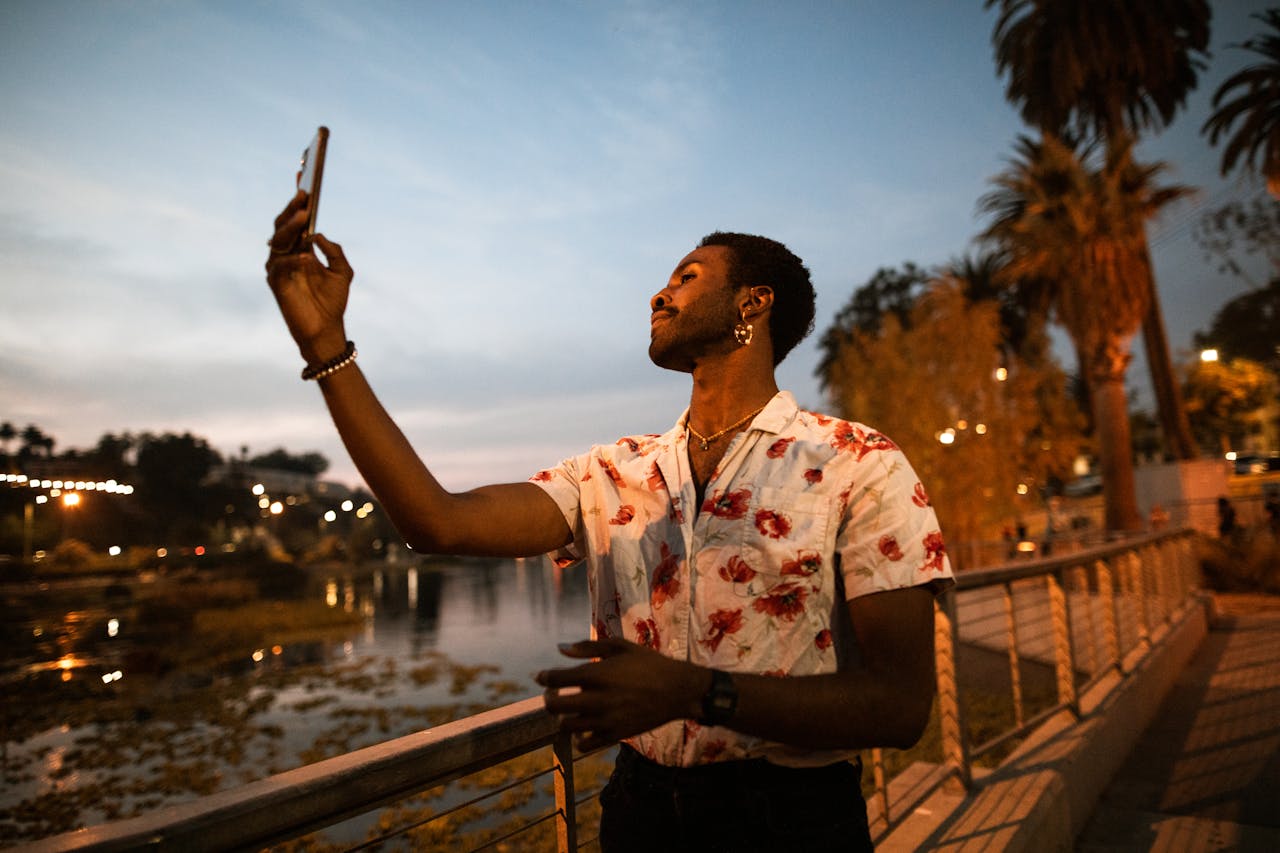 A self-assured man takes a selfie at sunset, showcasing diversity and self-care.