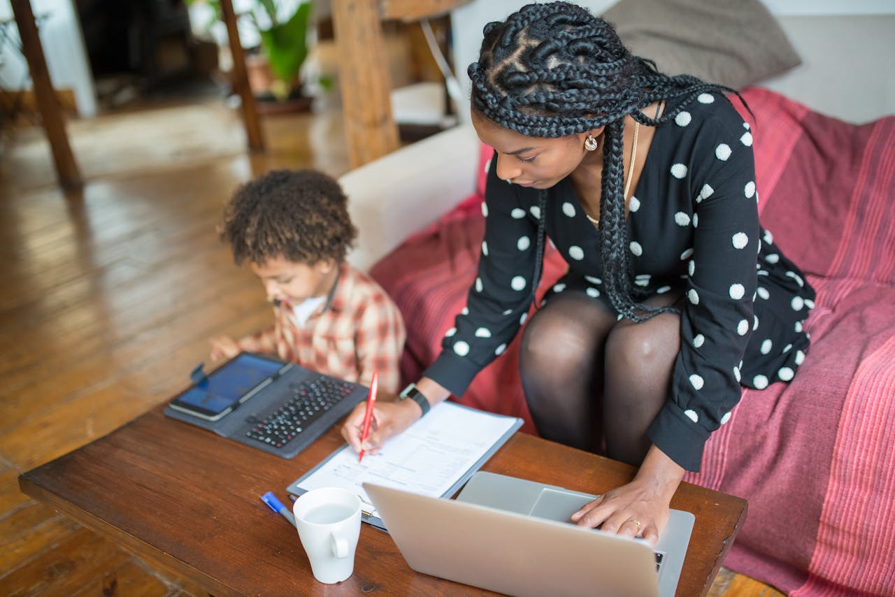 Mother multitasking with work and child at home, showcasing modern parenting.